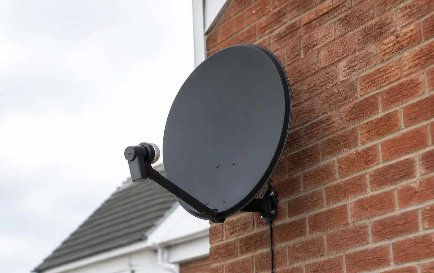 Engineer setting up a satellite dish on a house in Berkshire